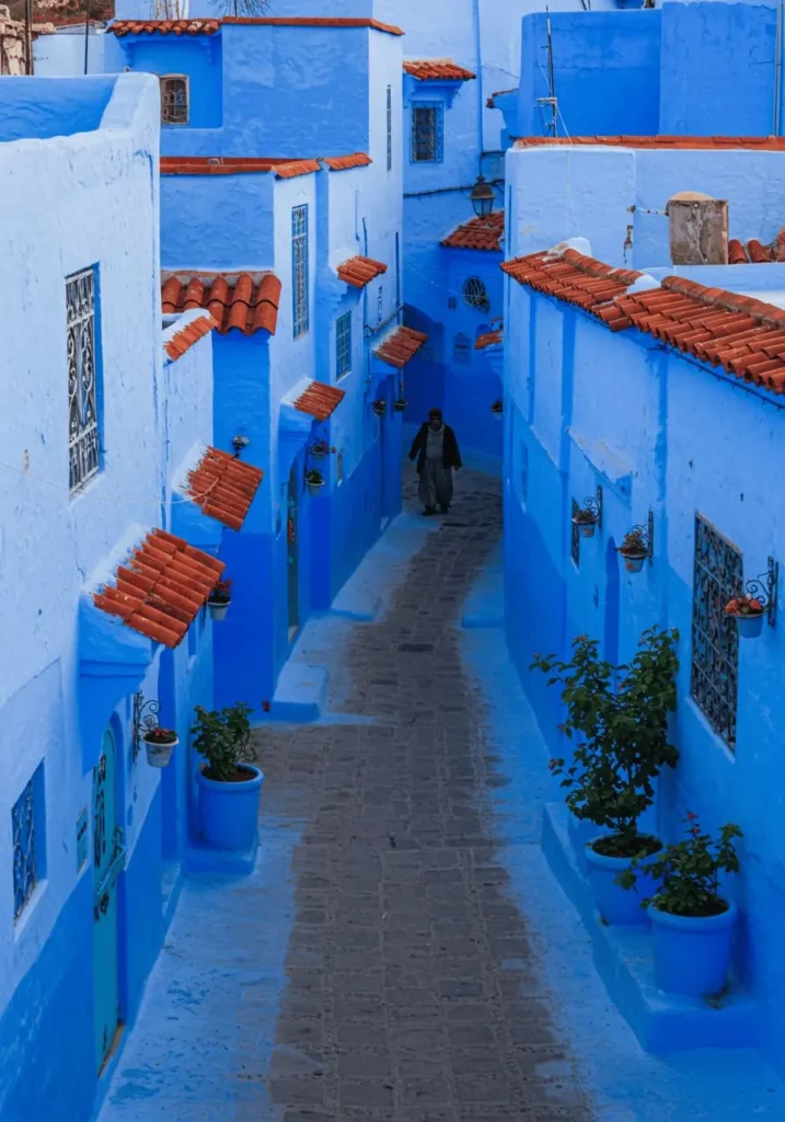 Blue streets of Chefchaouen, Morocco, with hanging laundry, potted plants, and a local walking past – offering a quiet, authentic glimpse into one of Morocco’s most beautiful towns.